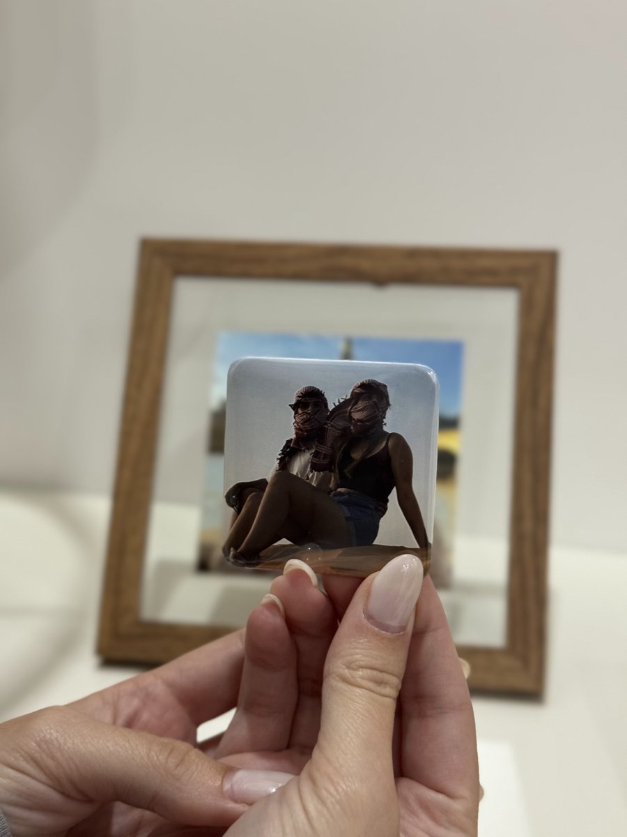 Mão a segurar um íman Liame com a foto de duas amigas